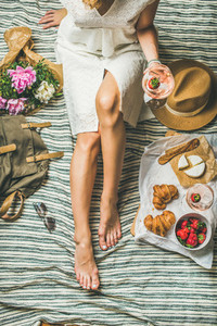 Girl in dress sitting on blanket with wine and snacks