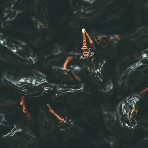 Flat lay of black dried raisins selective focus close up