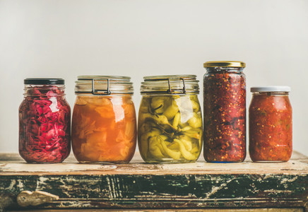Autumn pickled colorful vegetables in jars placed in row