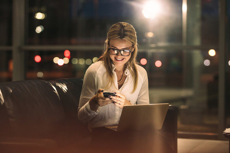 Businesswoman using phone while working late in office