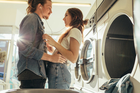 Couple in love standing together listening to music in laundry r