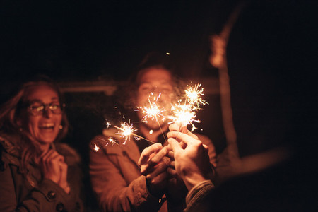 Friends lighting fire sparkles at night