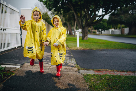 Twin sisters outdoors in raincoats