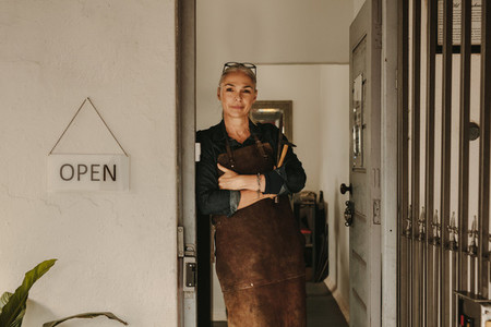 Female goldsmith standing at workshop door
