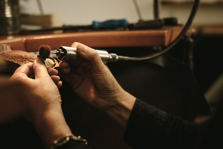 Jeweler polishing a gold ring at workbench