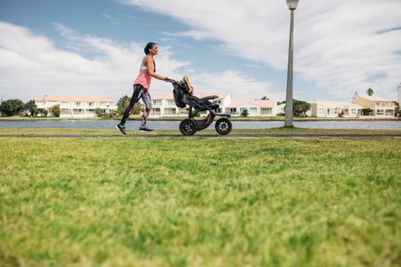 Mother running with a baby stroller in park