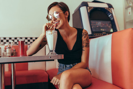 Woman sitting at a diner and sipping milkshake with a straw