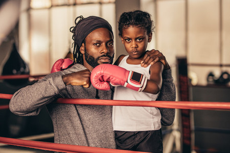 Boxing trainer with a kid boxer standing inside a boxing ring
