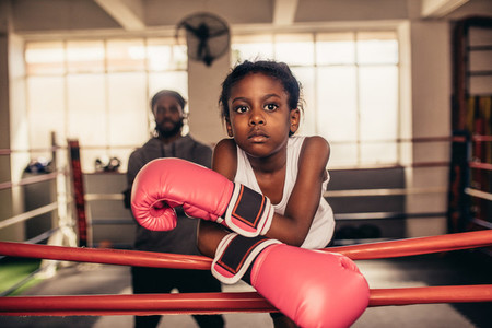 Girl wearing boxing gloves standing near a boxing ring