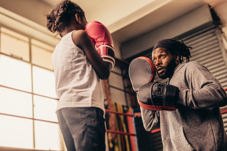 Low angle view of a boxing girl training with her coach