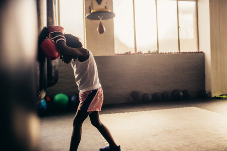 Side view of a tired boxing kid at a boxing gym