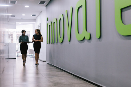 Female coworkers walking in office corridor