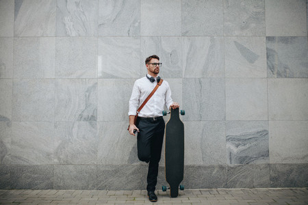 Businessman standing in street holding a longboard