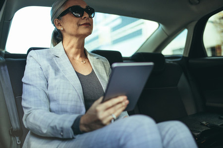 Senior businesswoman in car with tablet pc