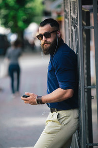 bearded man standing and listening to music