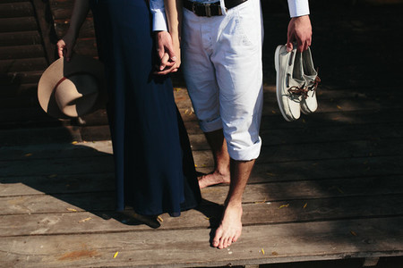 couple walk barefoot on pier