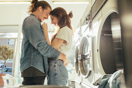 Happy couple embracing each other standing in a laundry room