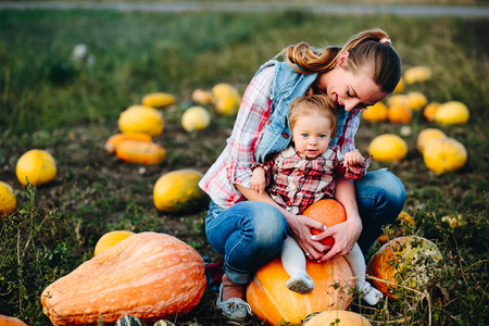 Mother and daughter sitting on pumpkins