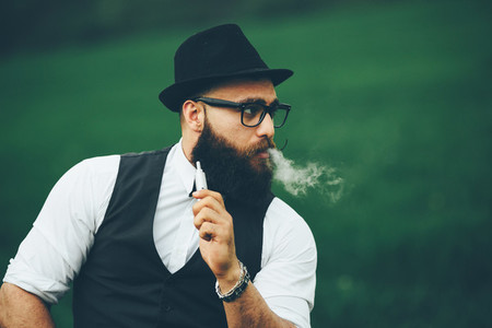 man with a beard smokes electronic cigarette