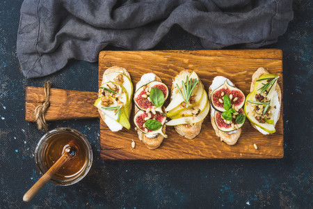 Crostini with fruits  cheese and herbs on rustic wooden board