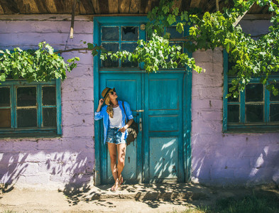 Girl standing near purple wall in Turkish village in summer