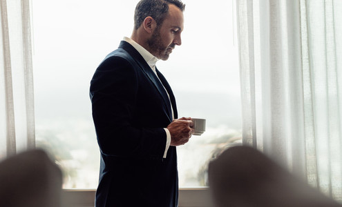 Businessman standing in hotel room having coffee