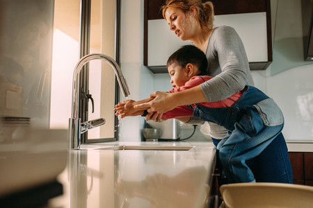 Son washing hands with mother in the sink