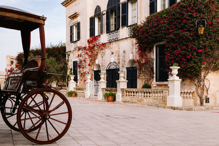 Ancient maltese house with orange bougainvillea in the wall and a buggy in the street