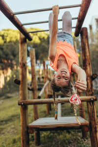 Girl hanging upside down on a horizontal ladder in a park