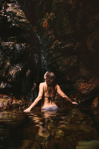 Woman enjoying in a waterfall pond