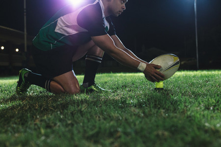 Rugby player placing the ball on tee for penalty