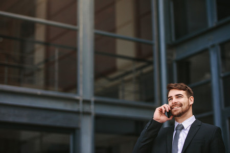 Positive businessman outdoors talking on phone