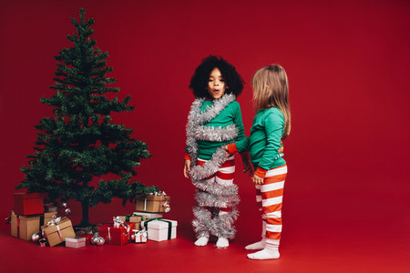 Kids having fun standing beside a christmas tree