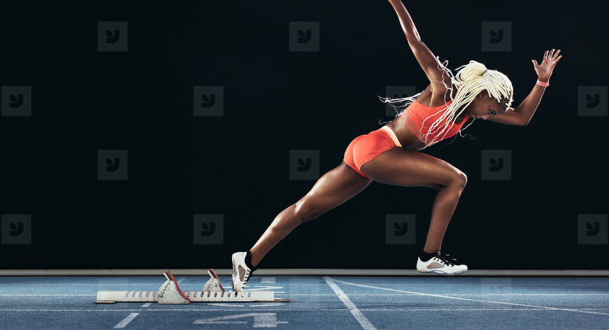Female sprinter taking off from starting block on a running trac