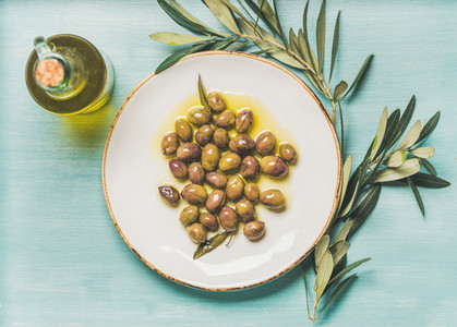 Pickled green olives  olive tree branch  virgin oil  blue background