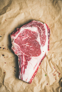 Raw steak rib eye with seasoning on craft paper copy space