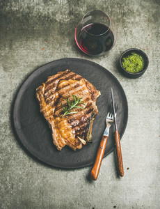 Grilled hot rib eye beef steak with red wine in glass
