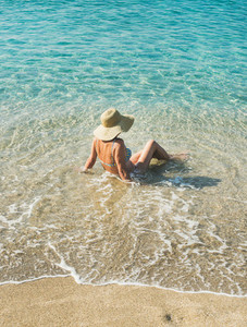 Senior woman tourist in bikini sitting at clear sea waters