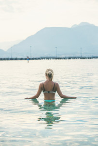 Young woman standing in still morning sea waters in Alanya