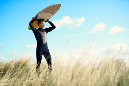 Strong young surfer crossing a sand dune