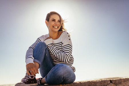 Smiling woman sitting on a sea wall