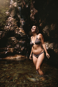 Woman wearing bikini standing inside a pond at forest