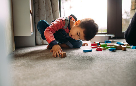 Little boy playing with colorful wooden blocks