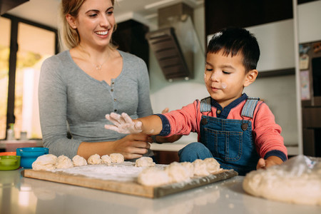 Little boy having fun making cookies with mother
