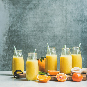 Healthy yellow smoothie with citrus fruit on wooden board