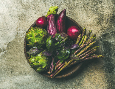 Flat lay of green and purple vegetables on plate  grey background