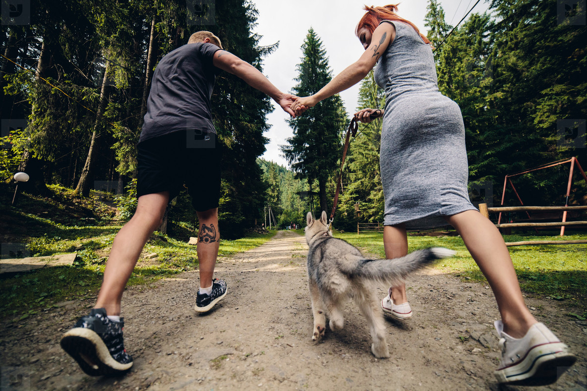 couple runs on road in the nature with dog