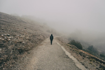Girl walking on a mountain road with a lot of fog