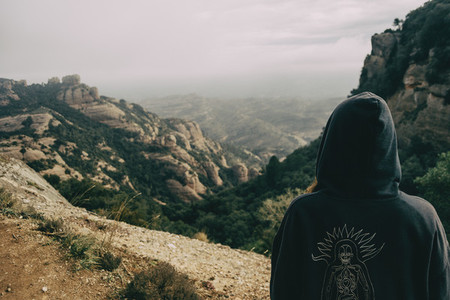 Girl on her back with a hood looking at a landscape of mountains