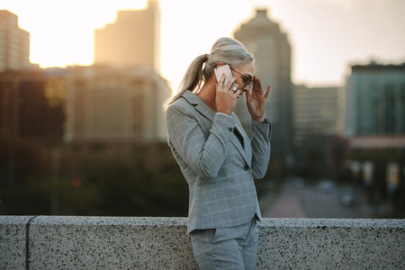 Senior businesswoman talking on phone on city bridge